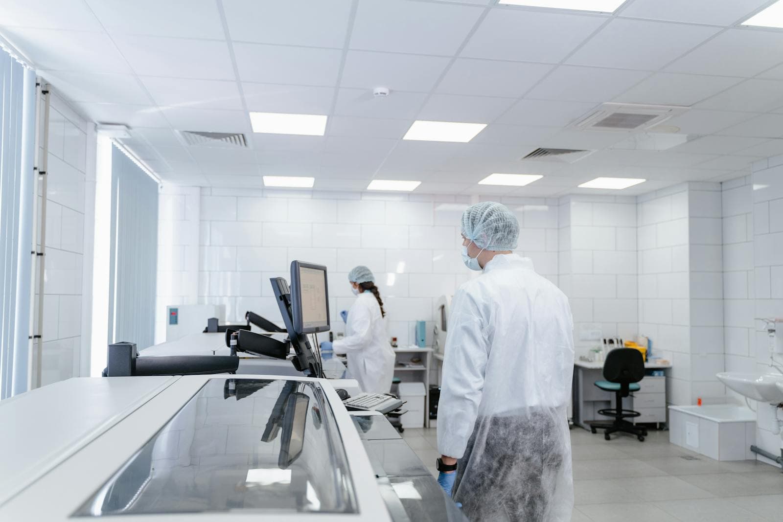 Cleanroom laboratory technicians in protective gear running compound analysis